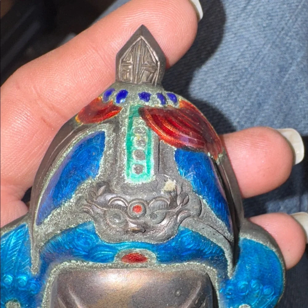 Vintage enameled metal decorative mask of an Asian man's face.